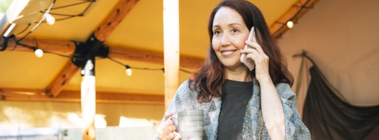 Woman talking on phone, holding a mug.